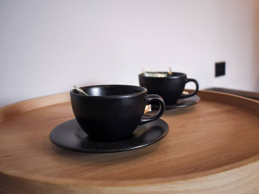 Dos tazas negras sobre una bandeja de madera.