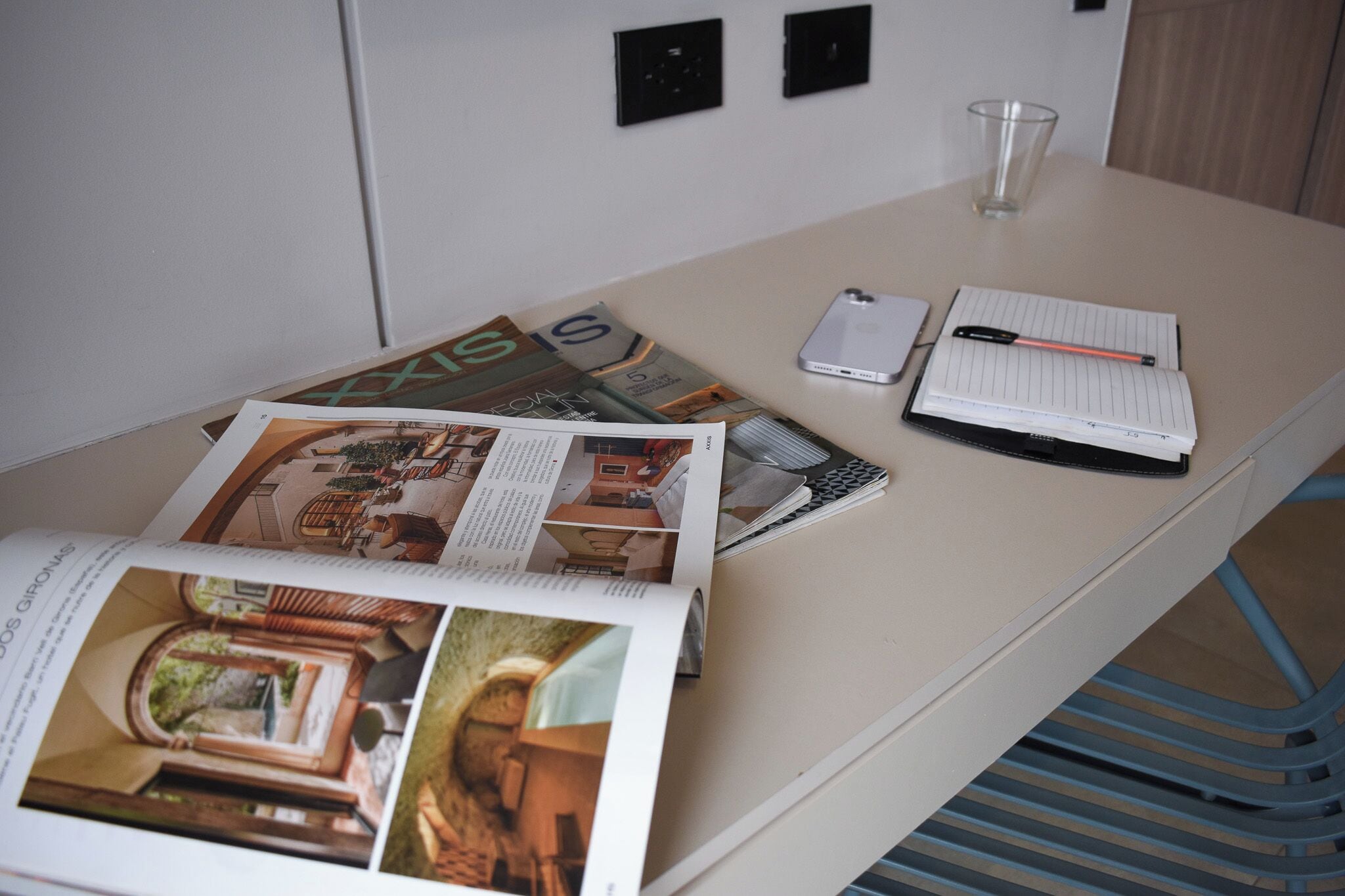 Un escritorio con una revista, un teléfono inteligente, un cuaderno y un bolígrafo.