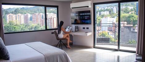 A modern hotel room with a large bed, a desk, and a TV.