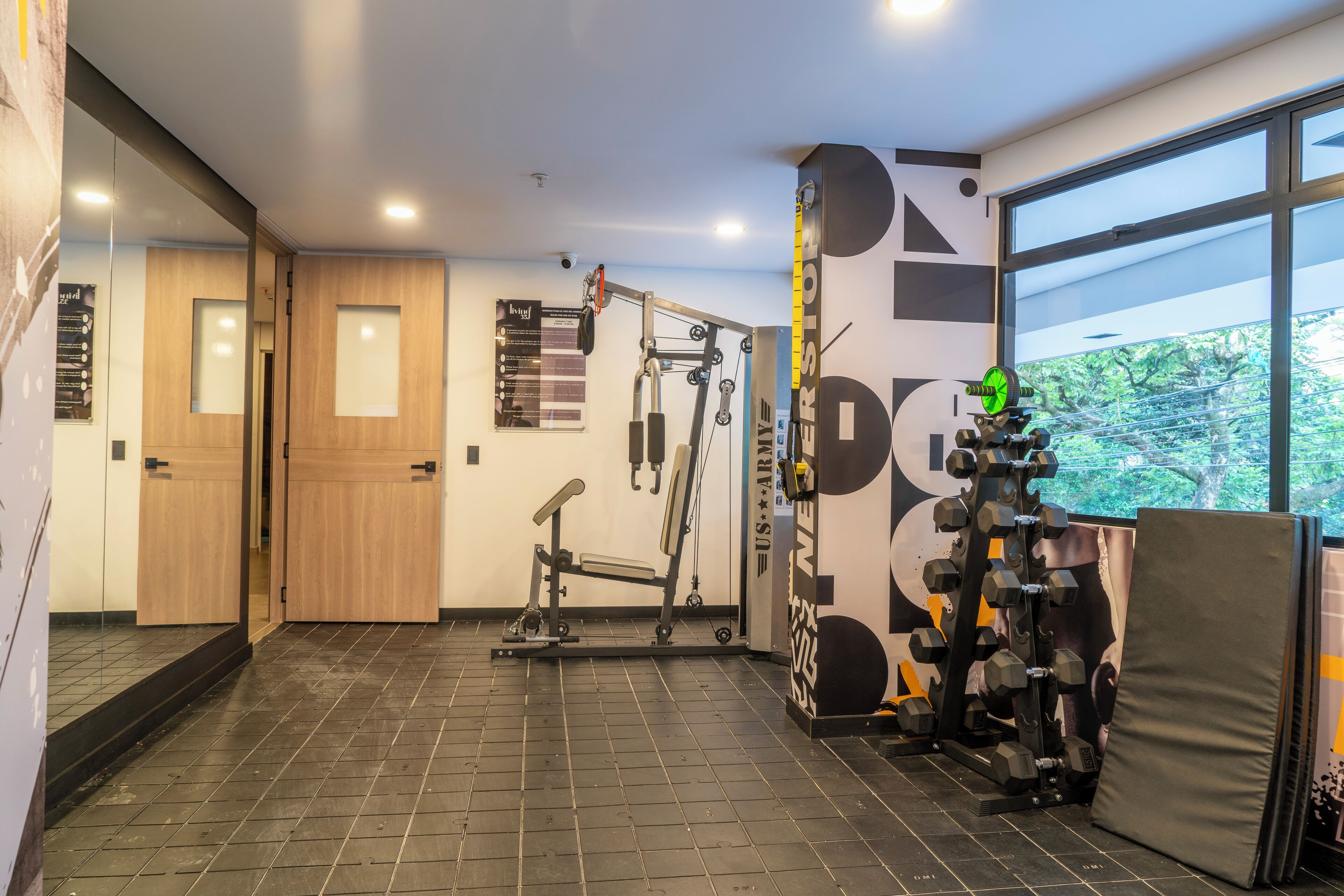 Un gimnasio con equipo de ejercicio, un ventanal y una puerta.