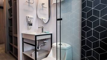 A modern bathroom with a white sink, two mirrors, a toilet, and a trash bin.