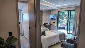 A modern hotel room with a bed, a desk, a TV, and a balcony with a view. - Hotel Living 35 Suites by Growing Group (Medellín)