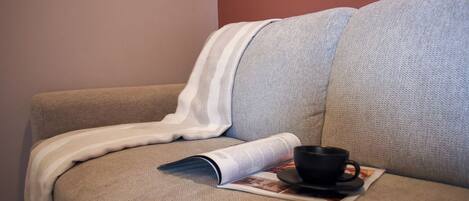A sofa with a magazine and a cup.