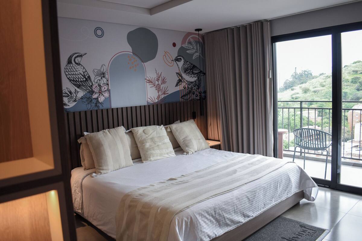 Een moderne slaapkamer met een groot bed, een balkon met een stoel en een muurschildering.