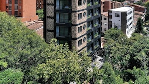 A modern high-rise building with multiple balconies, surrounded by greenery and other residential buildings. - Hotel Living 35 Suites by Growing Group (Medellín)