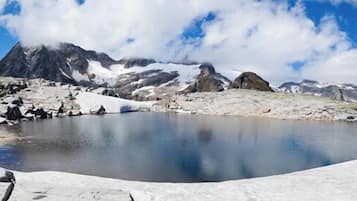Un lago montano tranquillo con sponde rocciose e cime innevate sullo sfondo.