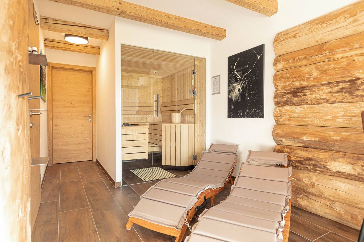 Un cuarto de sauna con bancos de madera y una puerta de vidrio que da a una zona de ducha.