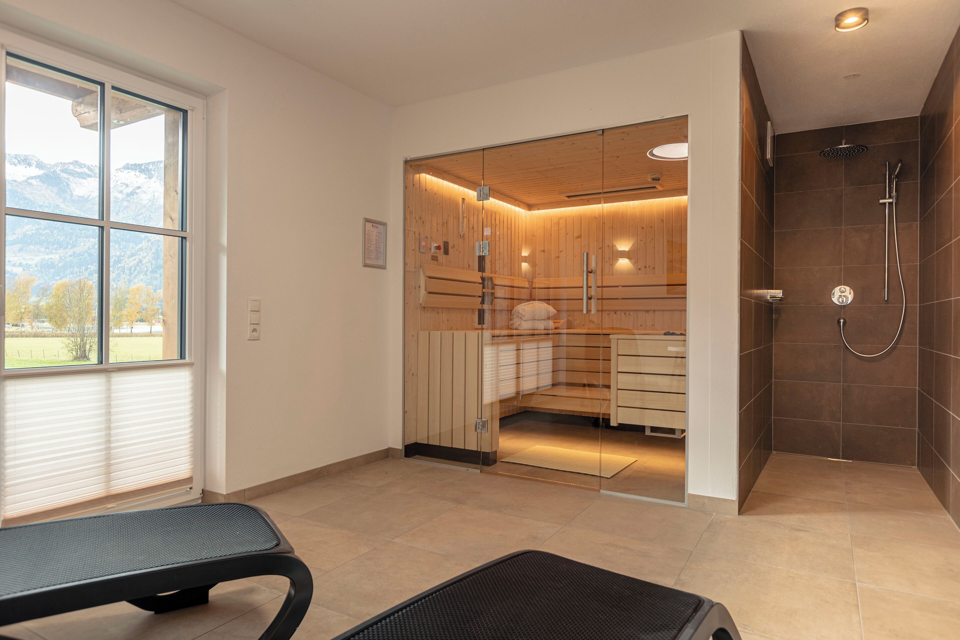 Un baño moderno con cabina de ducha de vidrio, sauna de madera y vistas al exterior.