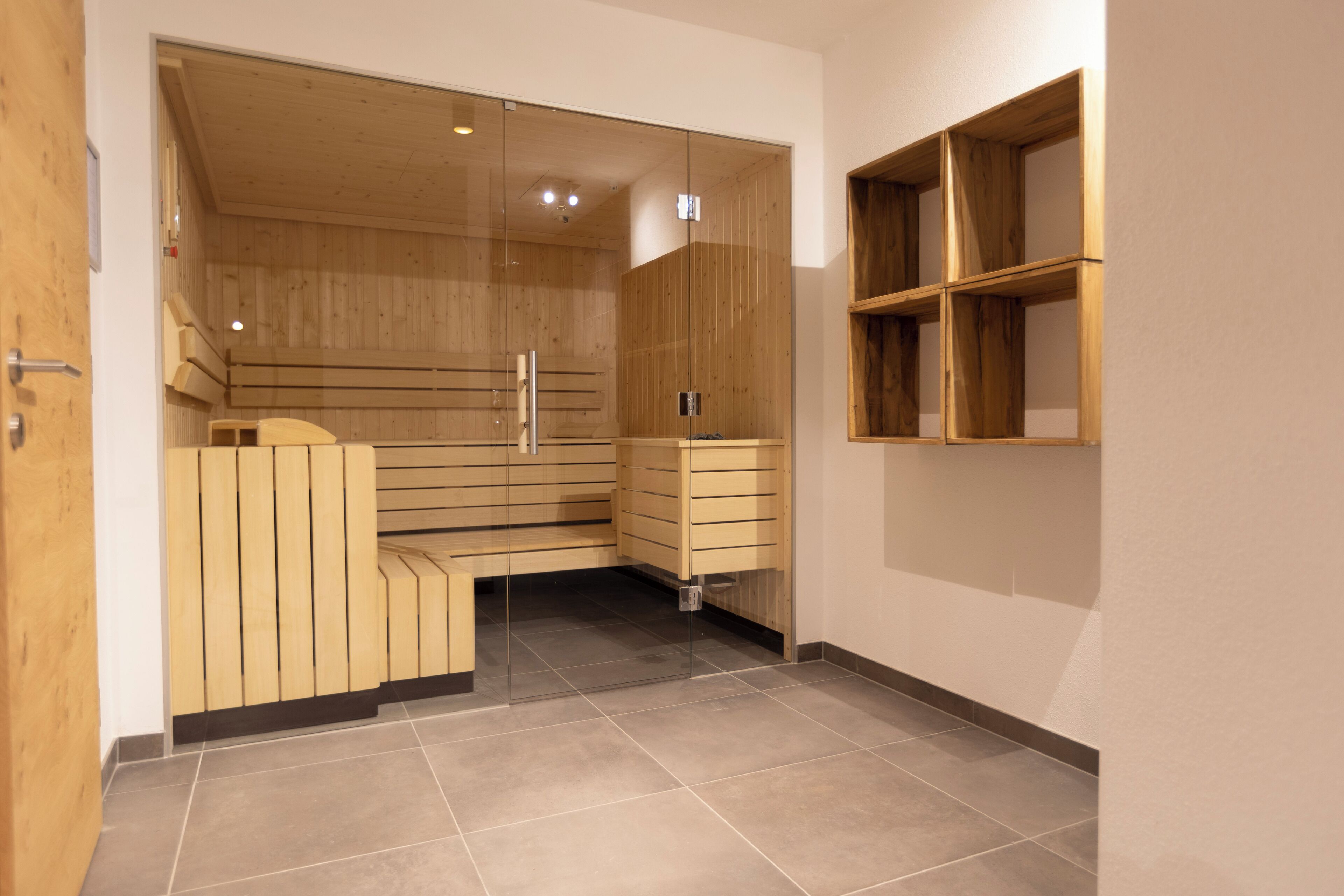 A modern sauna room with wooden benches and a glass partition.