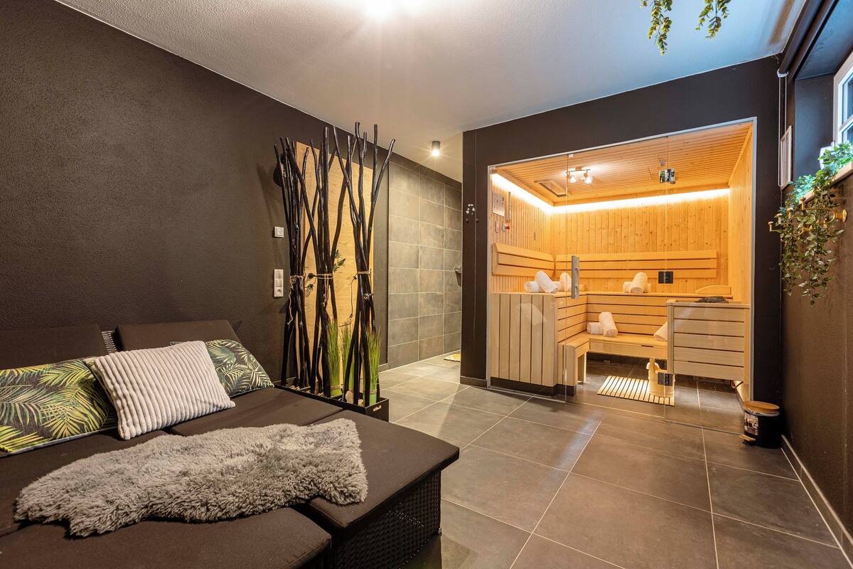 Un spa moderno con sauna de madera, camilla de masaje y zona de estar con alfombra mullida.