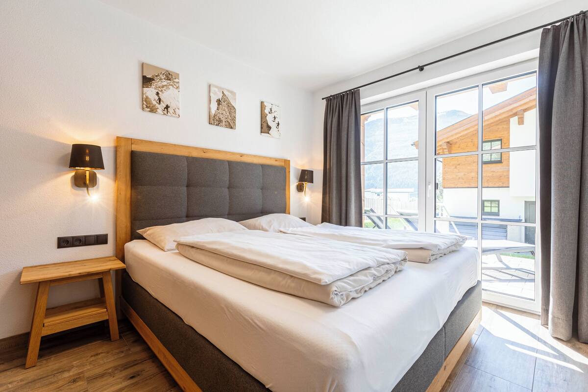 Una cama doble con cabecera de madera, dos mesitas de noche y lámparas de pared.