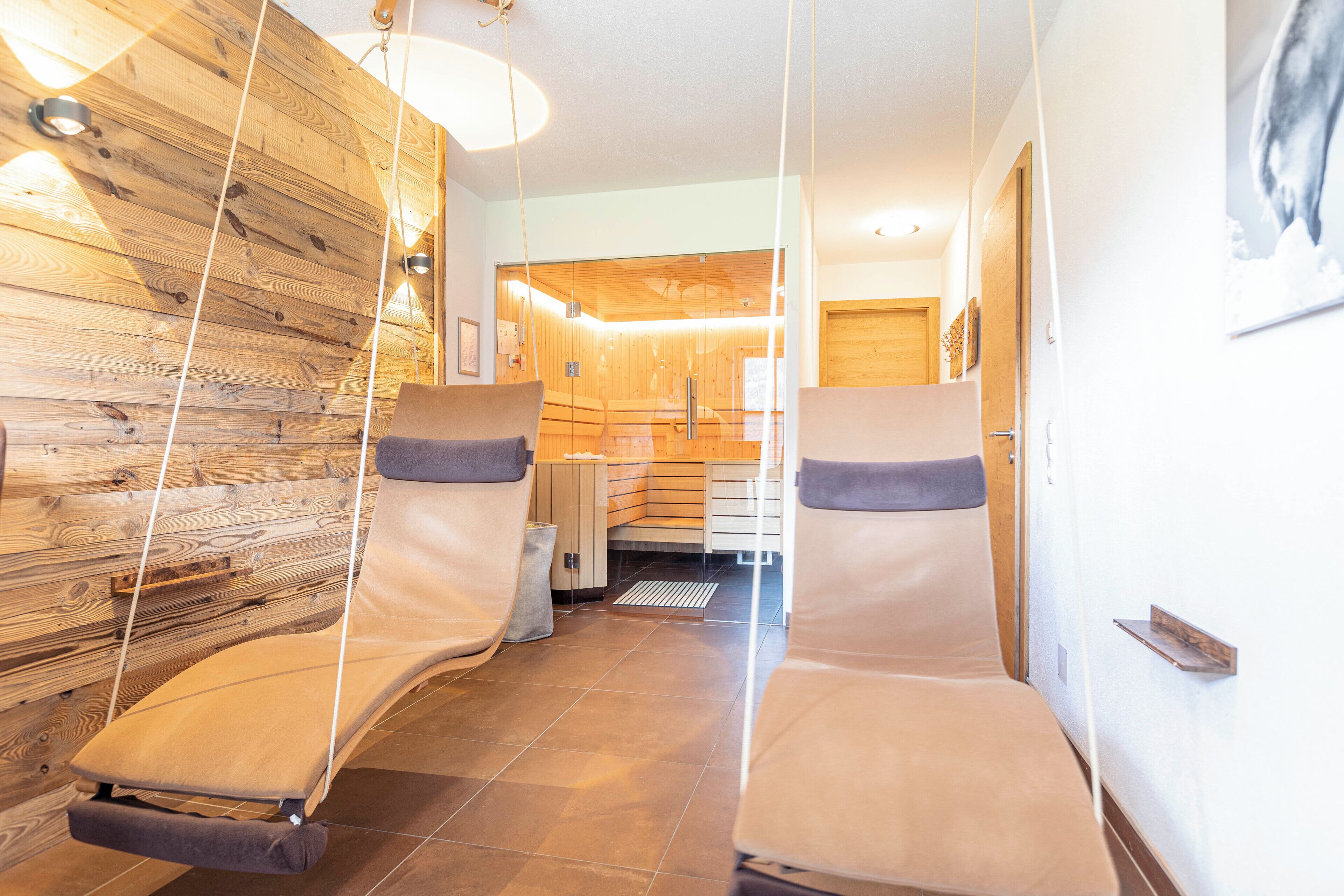 Un cuarto de spa con paredes de madera, dos sillas de masaje y una puerta de madera.
