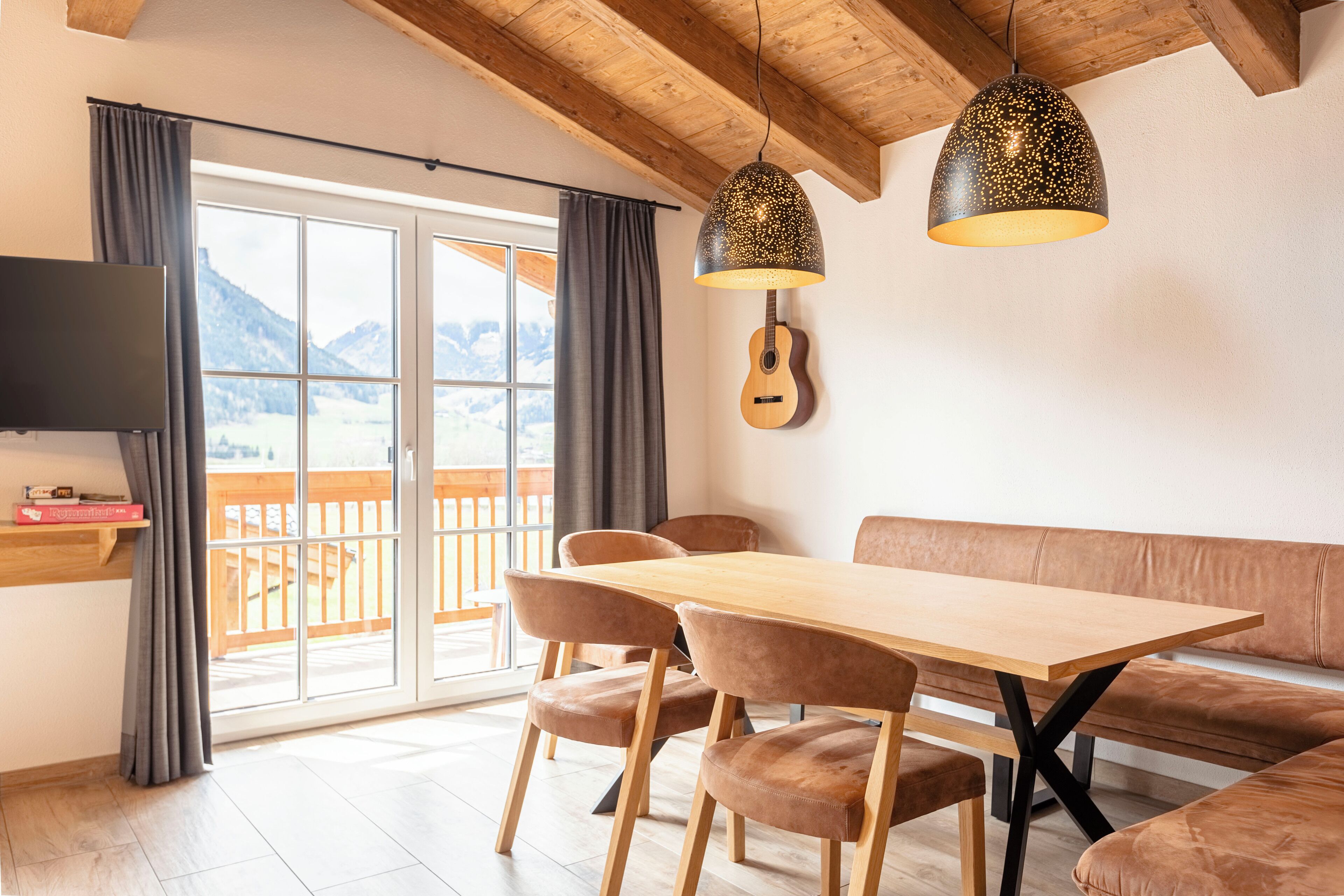 Un comedor moderno con una mesa y sillas de madera, un banco y una guitarra en la pared.