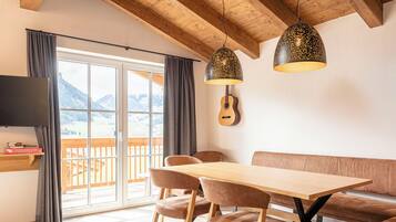Un comedor moderno con una mesa y sillas de madera, un banco y una guitarra en la pared.