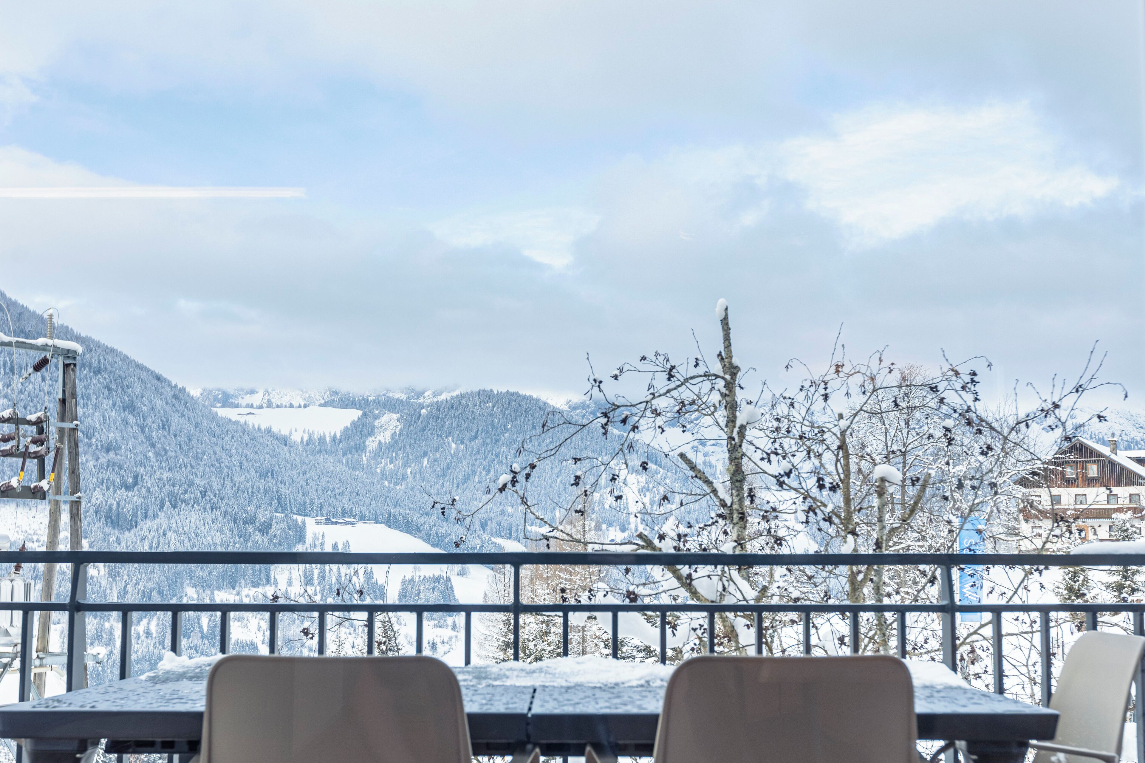 Vue sur une montagne enneigée depuis un balcon agrémenté d’une table et de chaises.