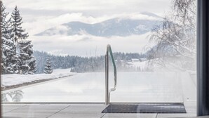 Interior moderno com vista para uma paisagem nevada e montanhas.