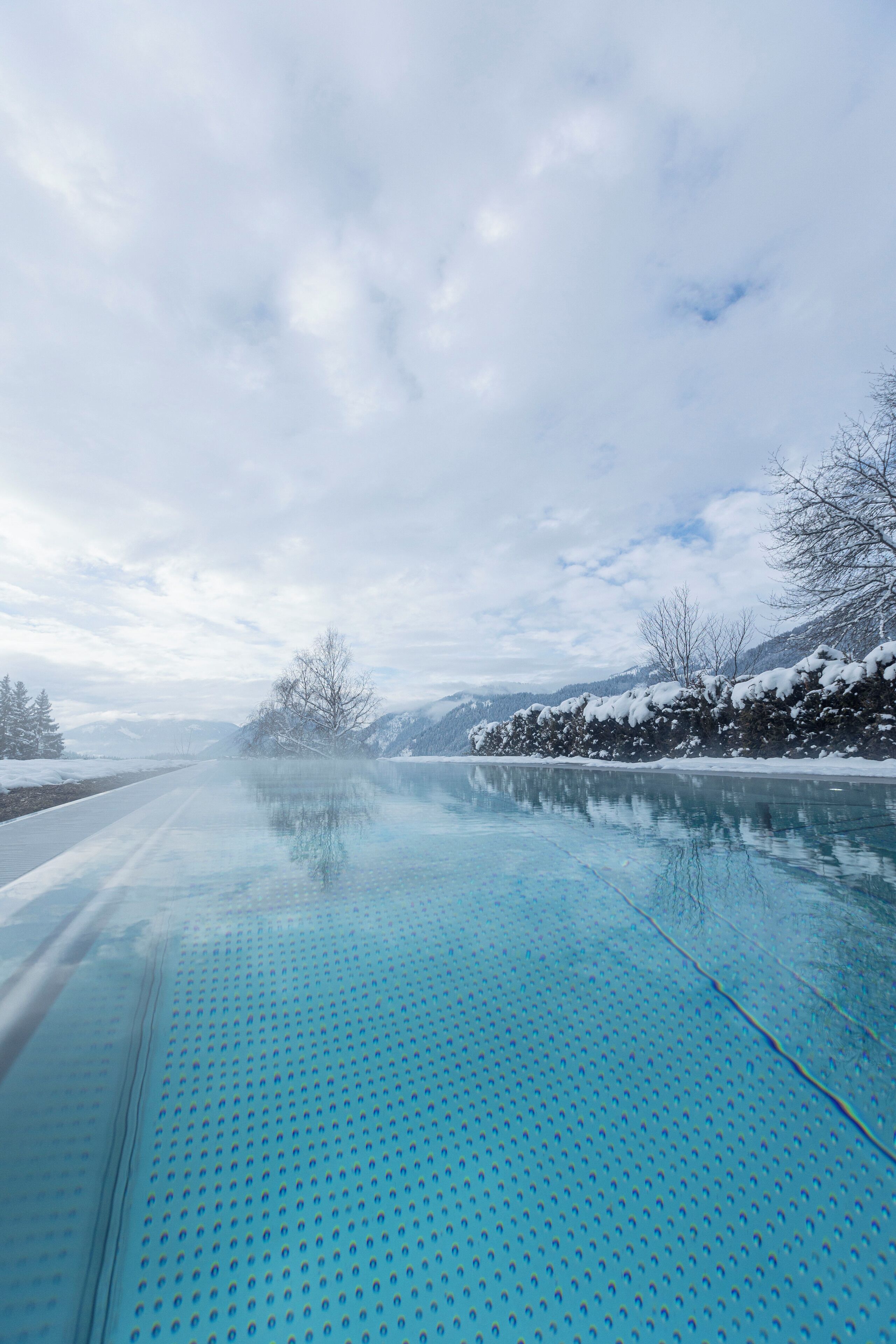 A clear, frozen lake with a metal walkway in the foreground.