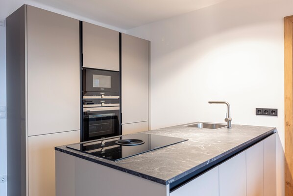 A modern kitchen with a built-in oven, a microwave, and a sink. - Hideaway Dachstein West by ALPS RESORTS (Sankt Martin am Tennengebirge)