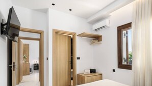A modern hotel room with a bed, a TV, an air conditioning unit, a mirror, and a wooden wardrobe.