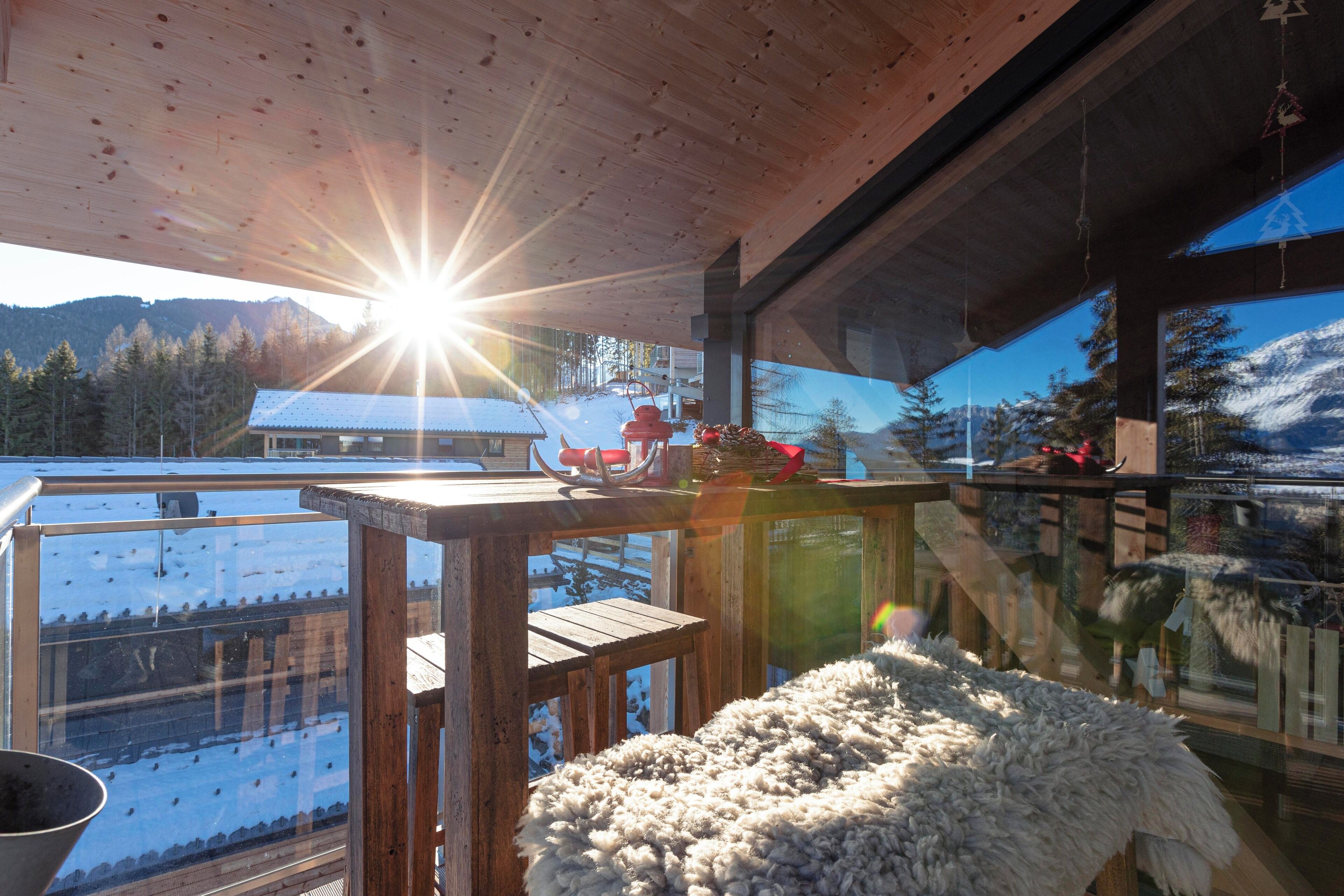 Eine Holzterrasse mit Blick auf eine verschneite Landschaft und Berge.