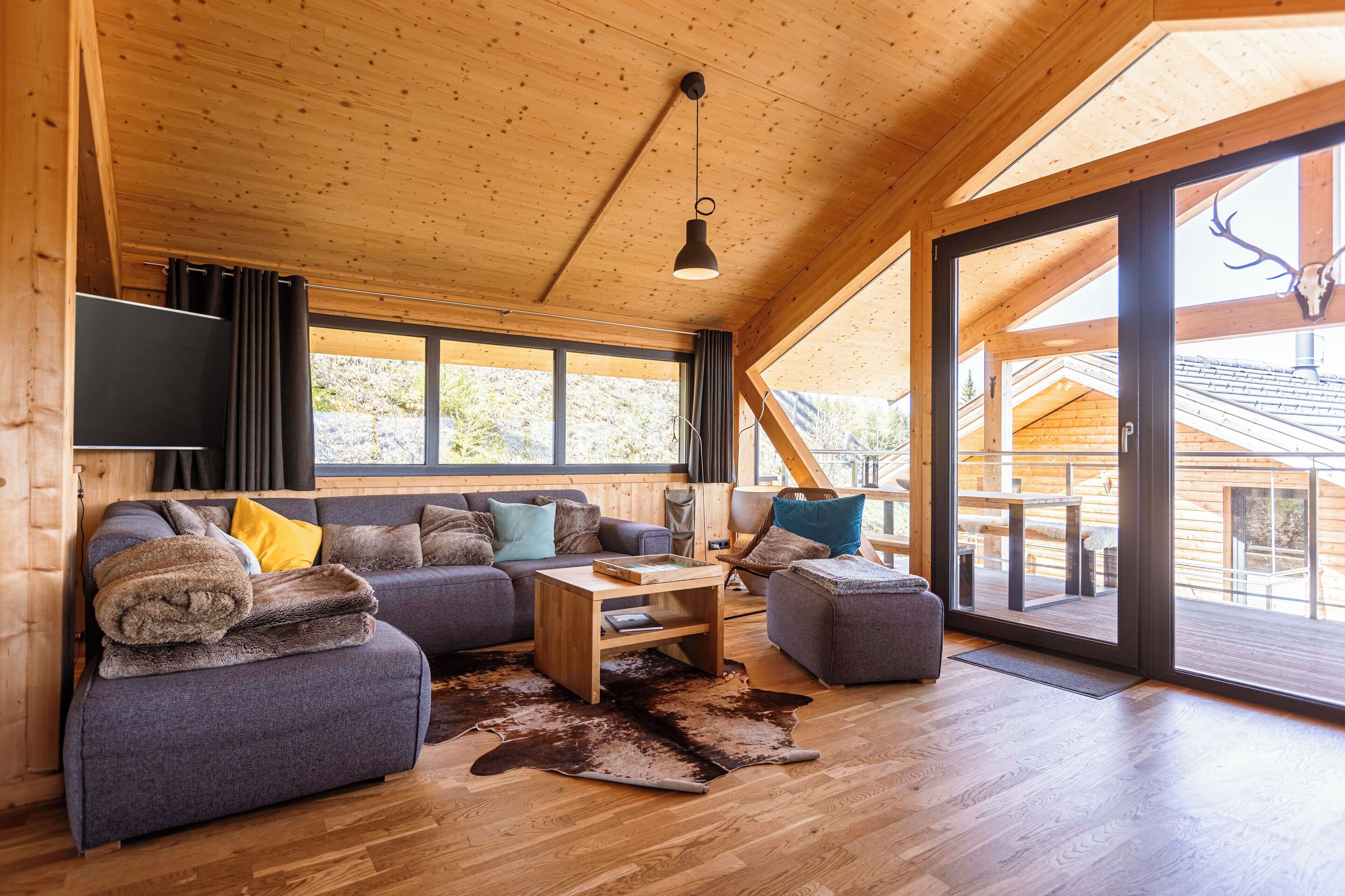 A modern log cabin interior with a sofa, ottoman, and a wooden coffee table.