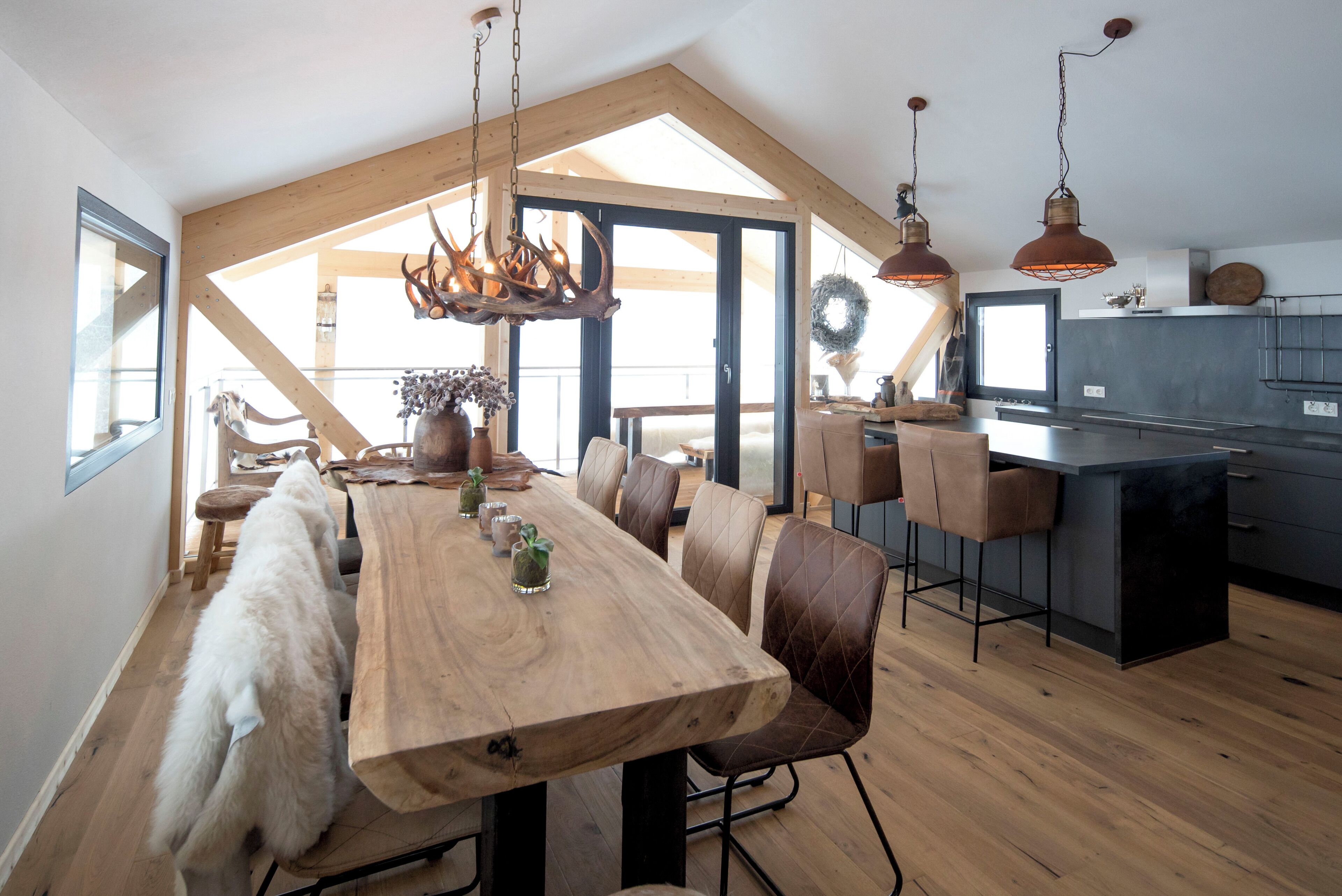 A spacious dining area with a long wooden table, leather chairs, and a rustic chandelier.