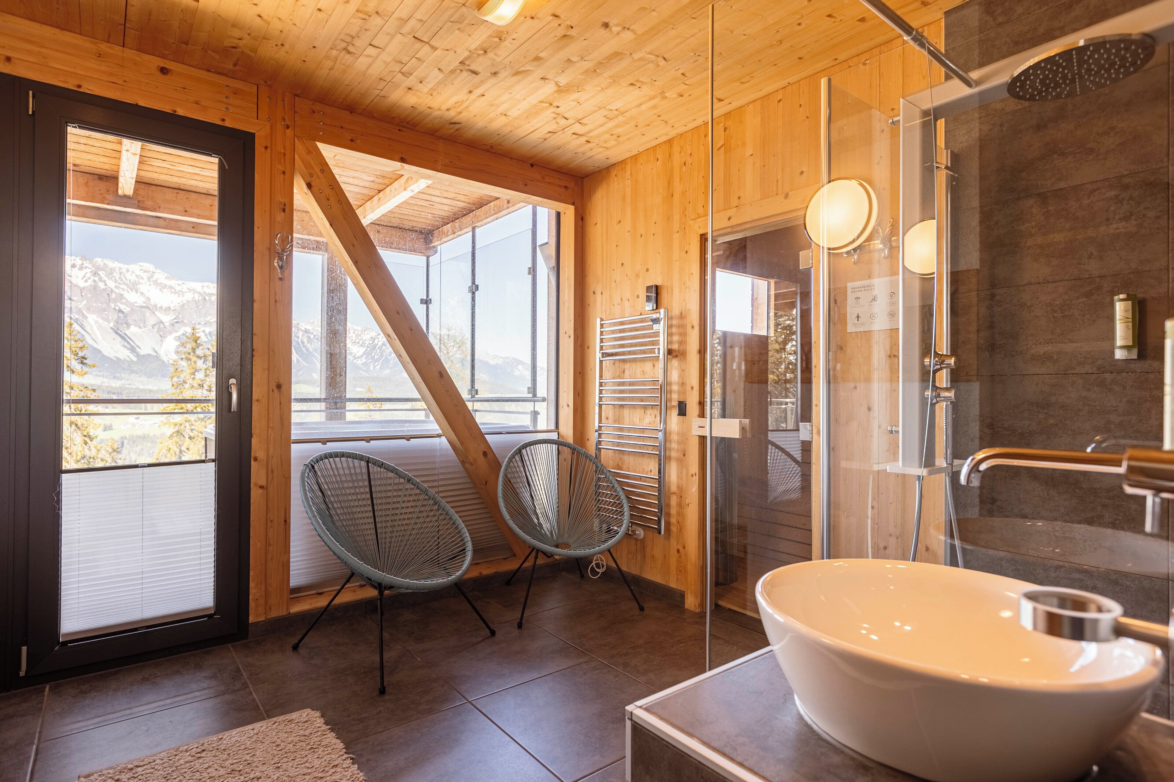 A wooden interior with a large window, a sink, and a shower.