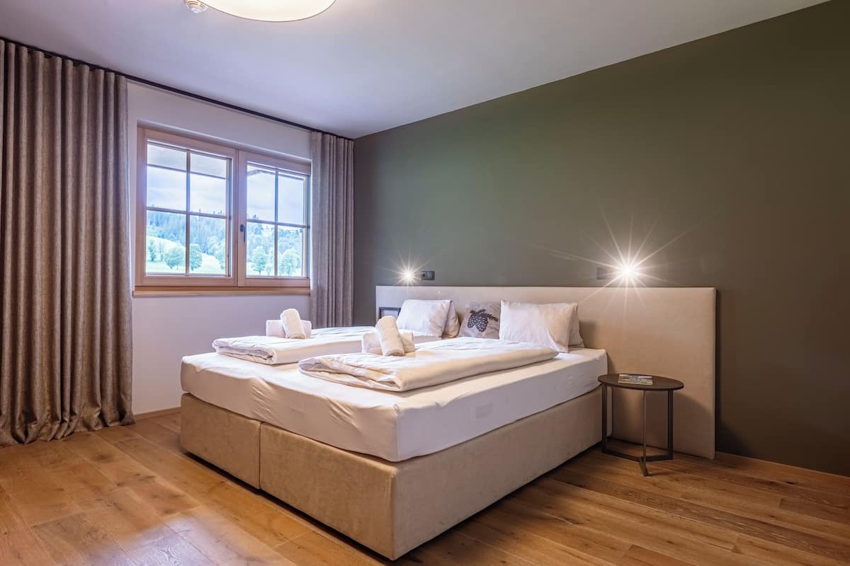 Ein modernes Schlafzimmer mit einem großen Bett, einem Nachttisch und einem Fenster mit Vorhängen.