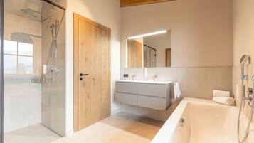 Ein modernes Badezimmer mit einer Duschkabine aus Glas, einer Holztür, einem großen Spiegel und einer Badewanne.