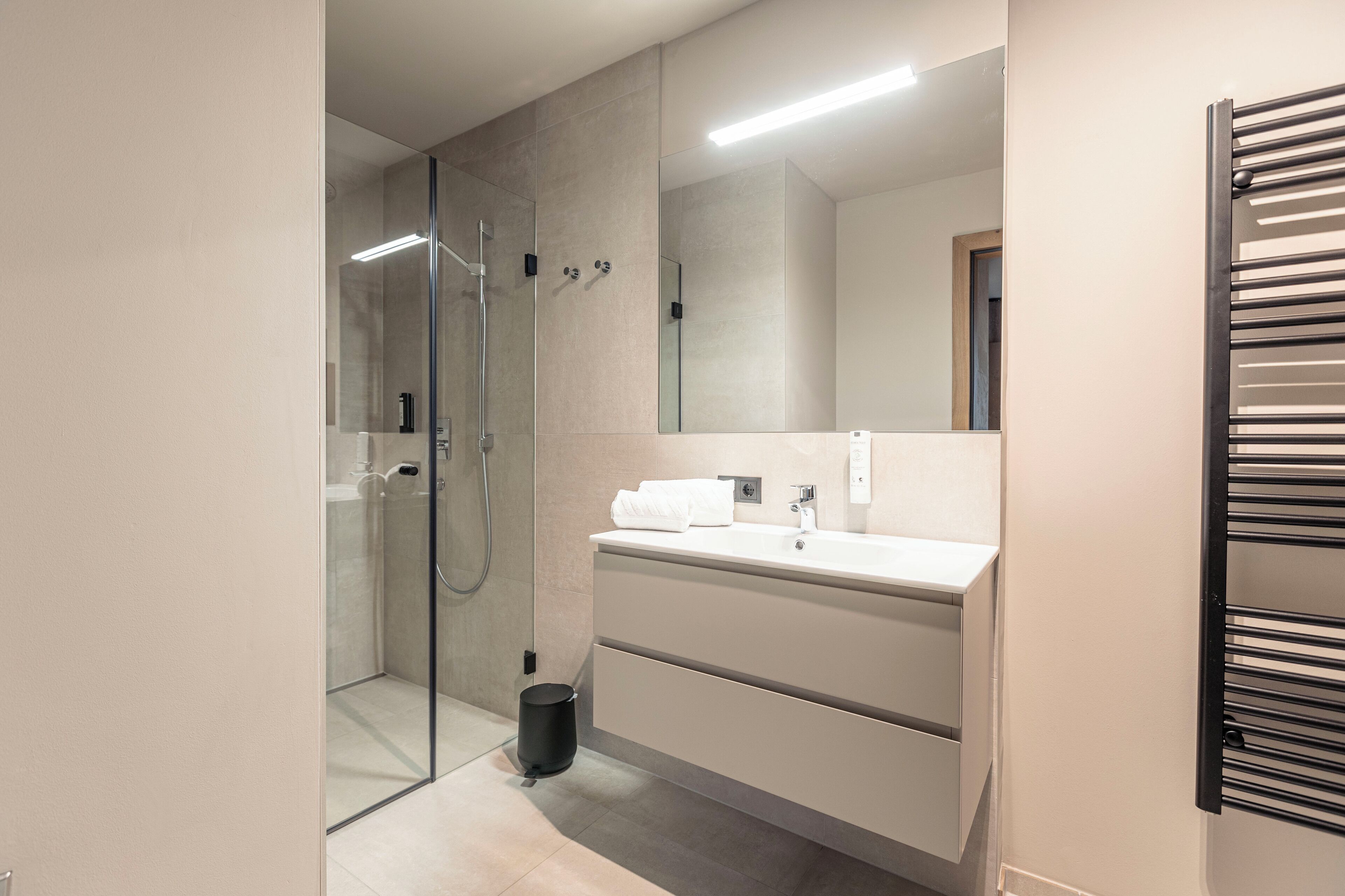 Un bagno moderno con doccia vetrata, lavabo bianco e uno specchio grande.