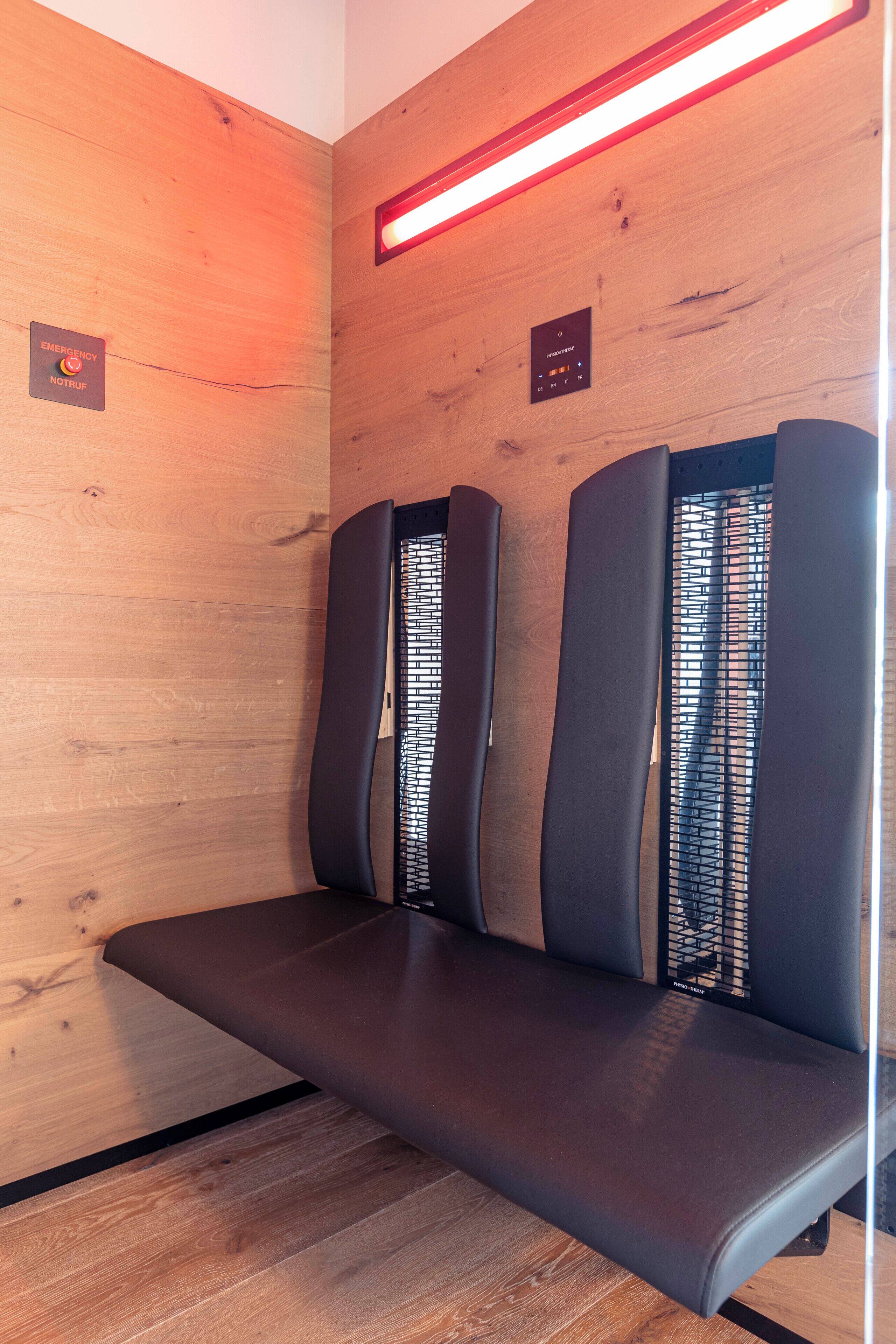 A wooden wall with two massage chairs and a red light strip.