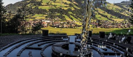 A circular stone water feature with a clear view of a town and mountains in the background.