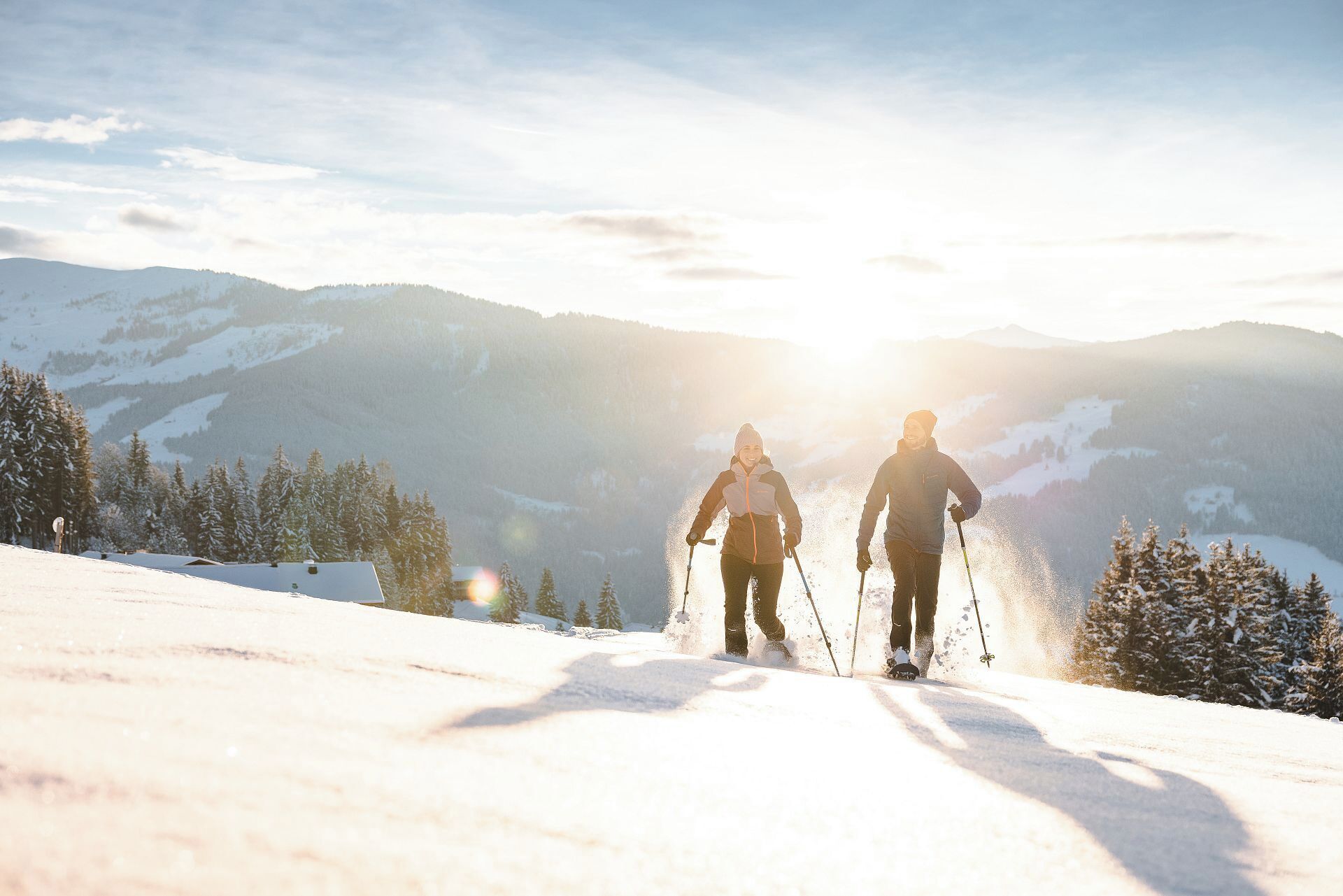 Two people skiing on a snowy slope with a mountain backdrop.