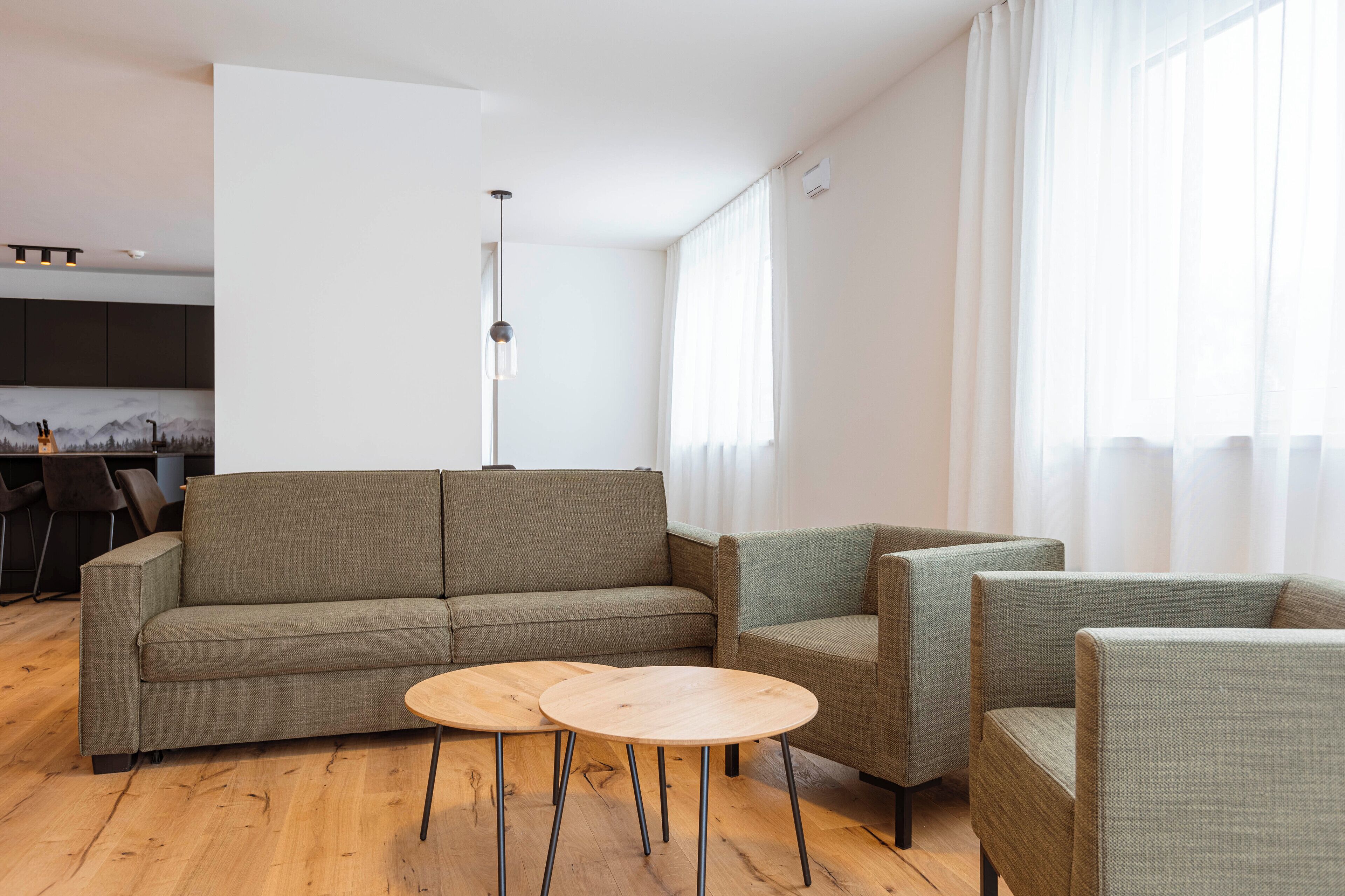 Un salon moderne avec un canapé, deux fauteuils et une petite table en bois.