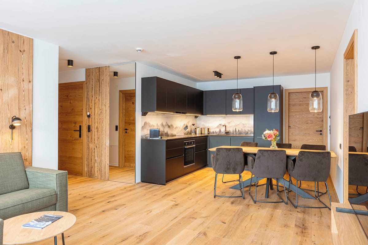 A modern kitchen with dark cabinets, a wooden island, and pendant lighting.