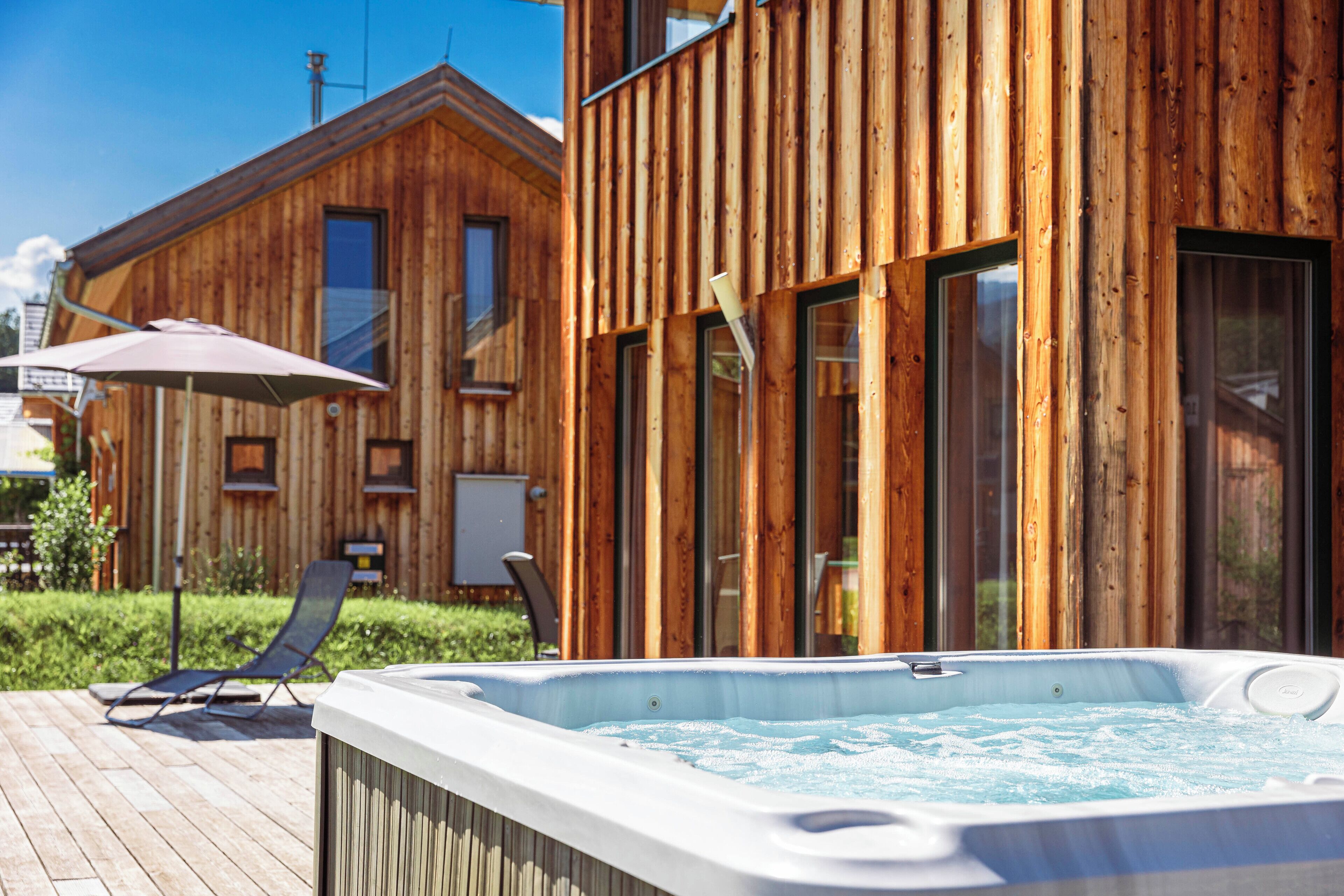 A wooden cabin with a hot tub and a lounge chair.