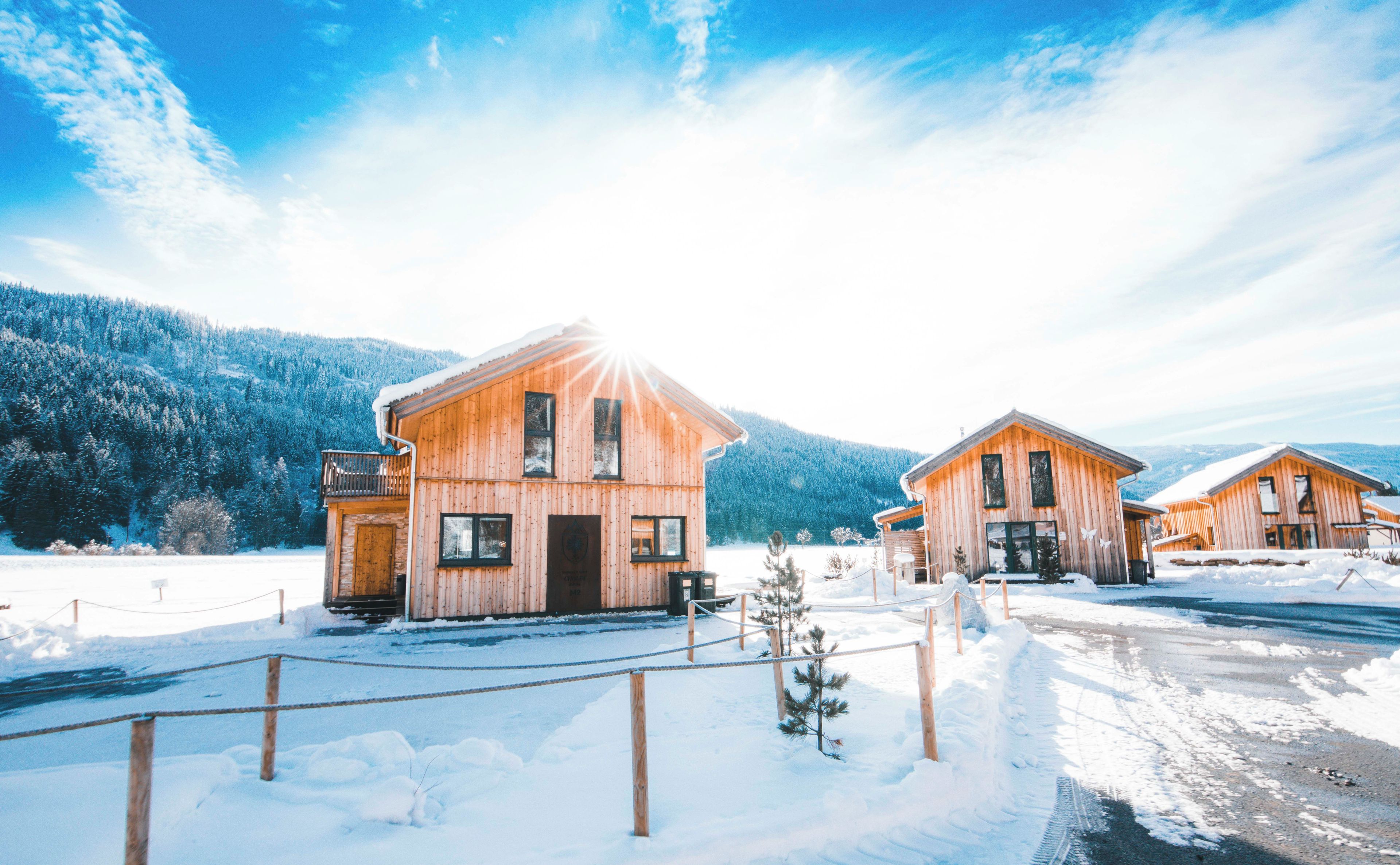 Una cabaña de madera con balcón, rodeada de nieve y montañas.