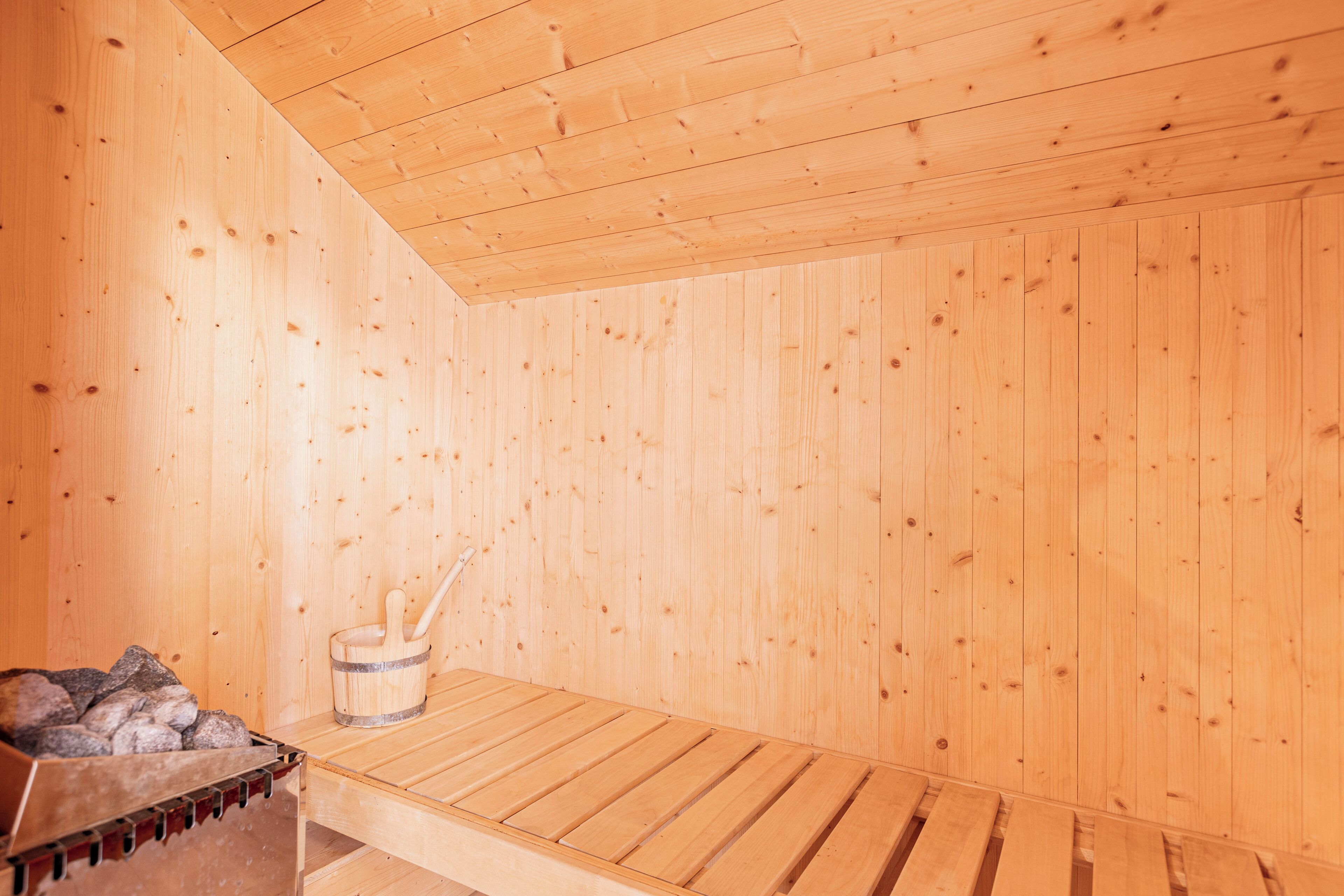 Un sauna avec des murs en bois et un banc.