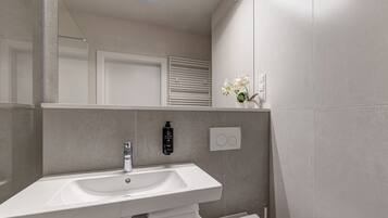 A modern bathroom with a white sink, a mirror, and a towel rack.