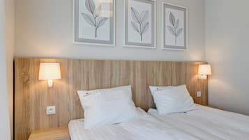 A neatly made bed with white linens, two bedside lamps, and a wooden headboard.