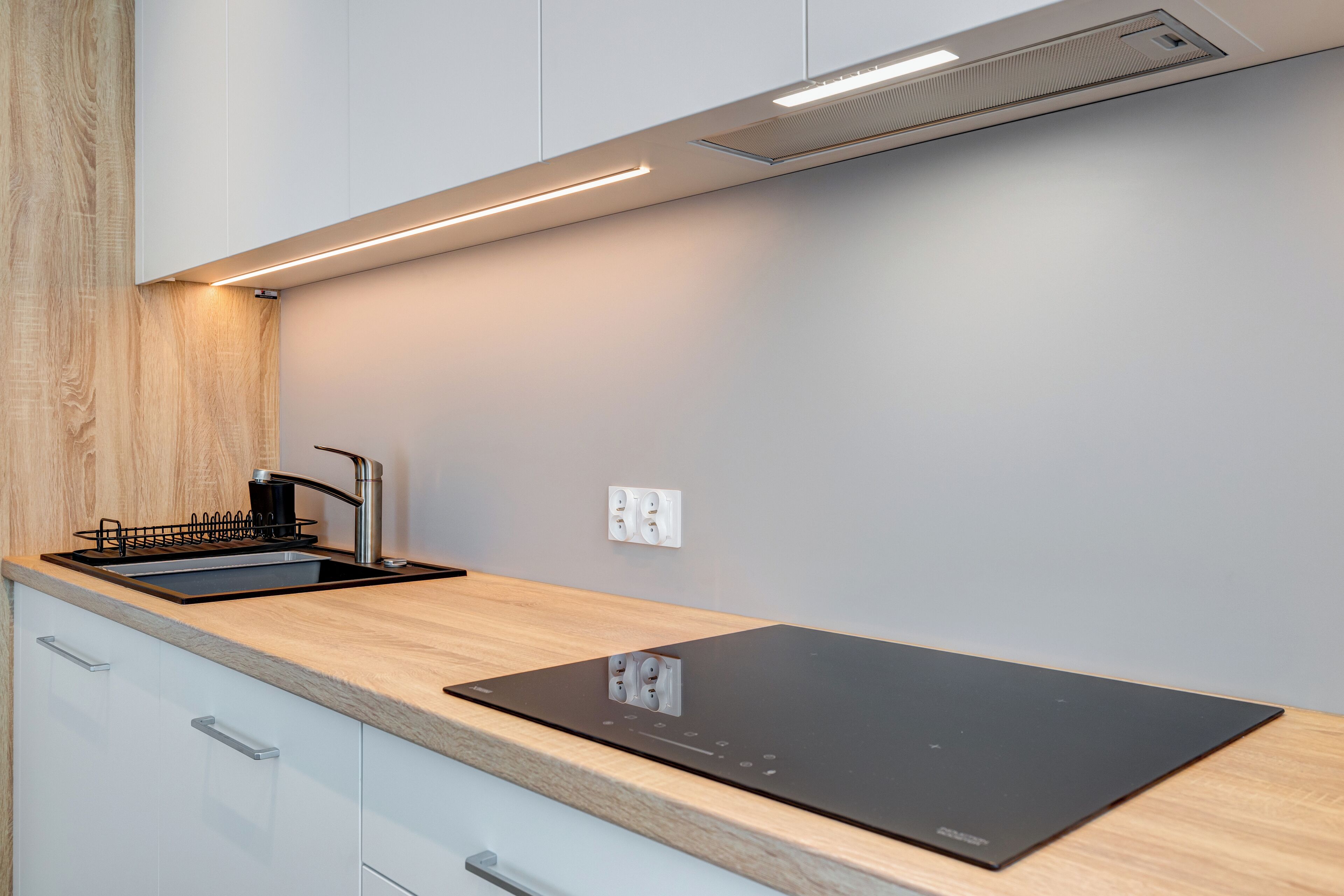 A modern kitchen with a built-in stove, a sink, and a wooden countertop.