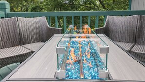 A glass-top table with a built-in grill, surrounded by wicker chairs, set on an outdoor deck with a green railing. - Hot Tub, Lake, and LOCATION! Fall Hiking, Adventures and Relaxation (Albrightsville)