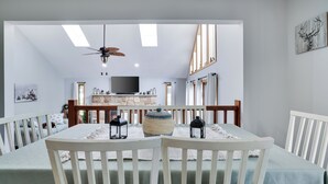 A dining area with a table set for four, white chairs, a ceiling fan, and a television in the background. - Hot Tub, Lake, and LOCATION! Fall Hiking, Adventures and Relaxation (Albrightsville)