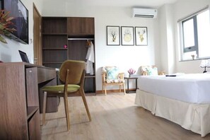 Comfortable room with a bed, desk, chair, and wardrobe, offering a functional space for work and relaxation.