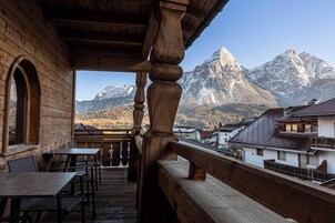 A wooden balcony with tables and benches overlooking a mountain landscape.