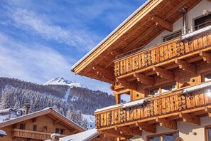 A wooden chalet with a balcony overlooking a snowy mountain. - Zugspitz Suites Lermoos by ALPS RESORTS (Lermoos)