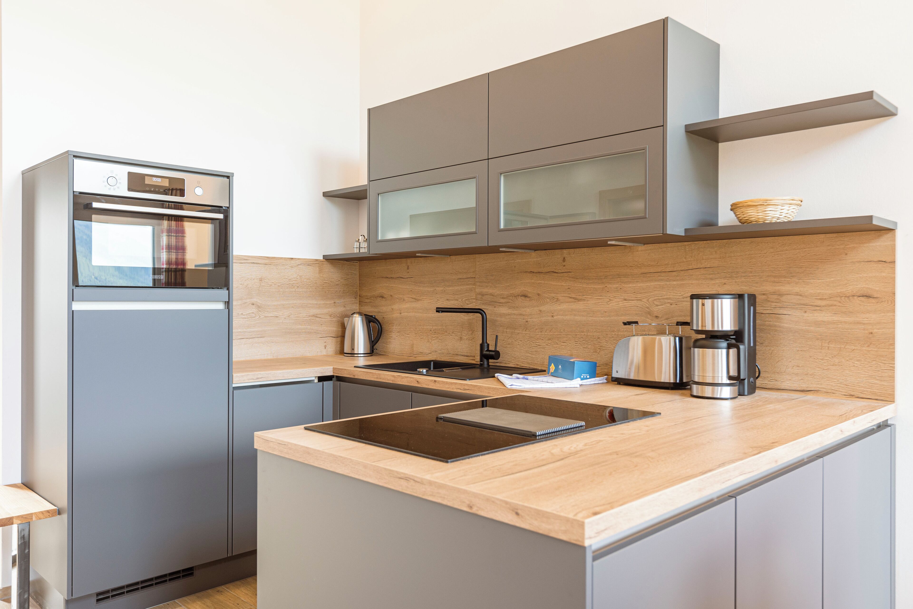 A modern kitchen with a built-in oven, a sink, and a coffee maker.