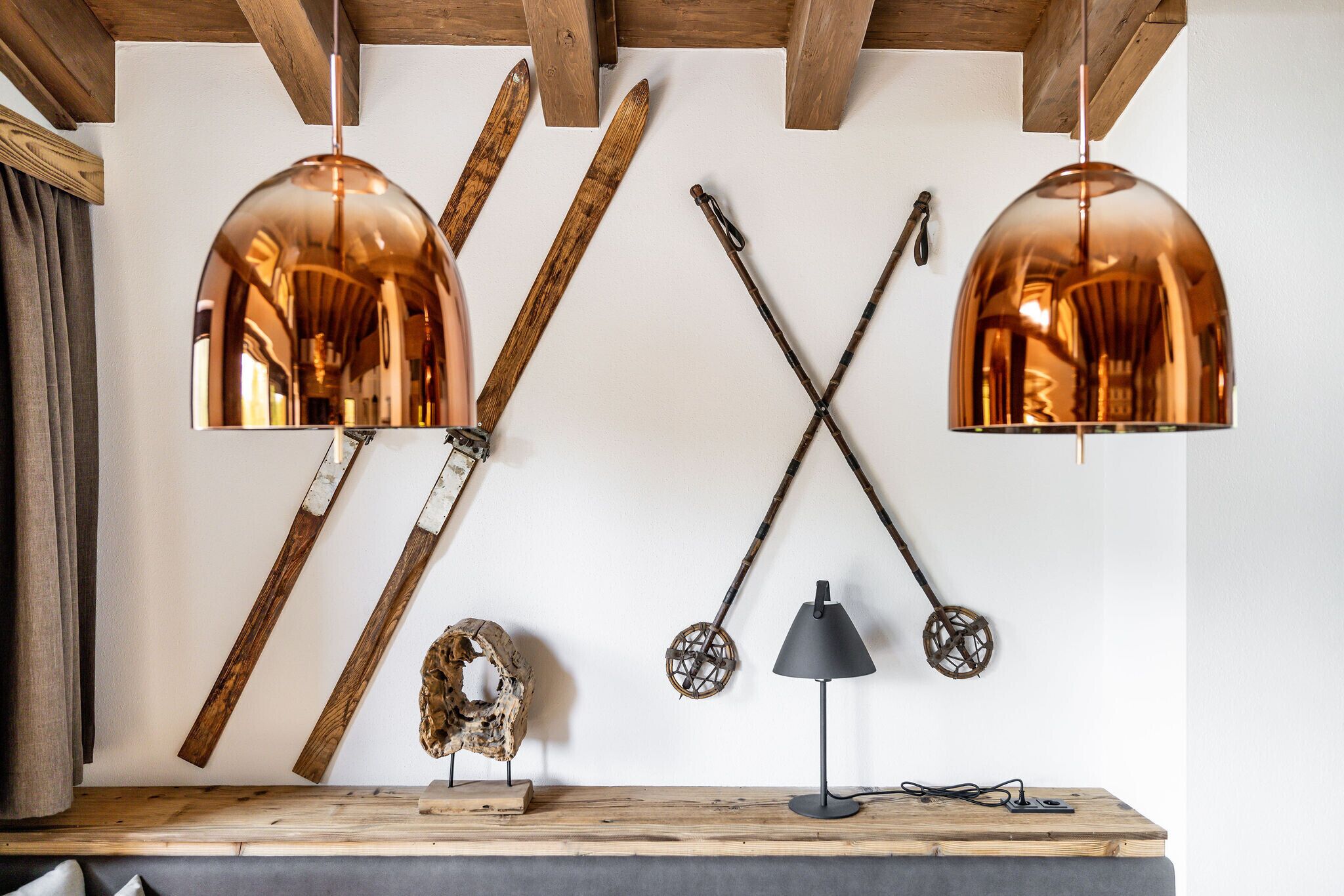 A wooden table with skis, a lamp, and a wall-mounted light fixture.
