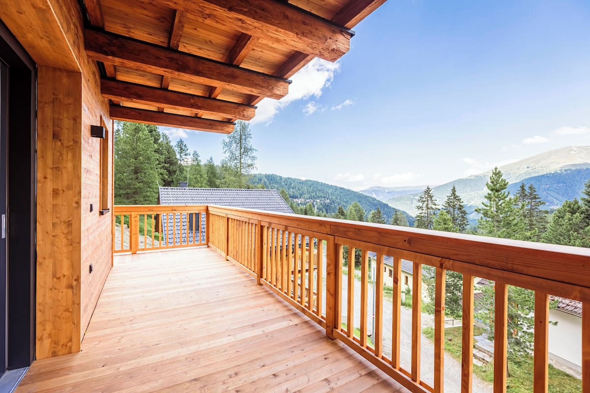 A wooden deck with a railing overlooking a mountainous landscape.