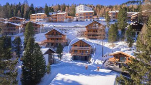 A snow-covered resort with multiple wooden cabins and a central building with a balcony. - Turrach Lodges by ALPS RESORTS (Stadl-Predlitz)